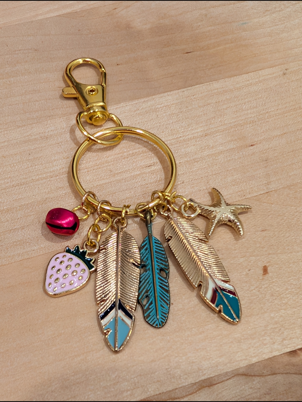 Gold Tone Feather Charm Keyring with Pink Strawberry and Jingle Bell Accents